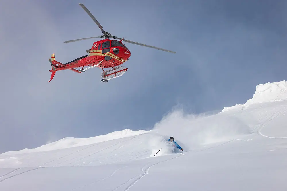 Helicopter hovering above a skier who is heli-skiing in the wasatch mountains with Powderbird