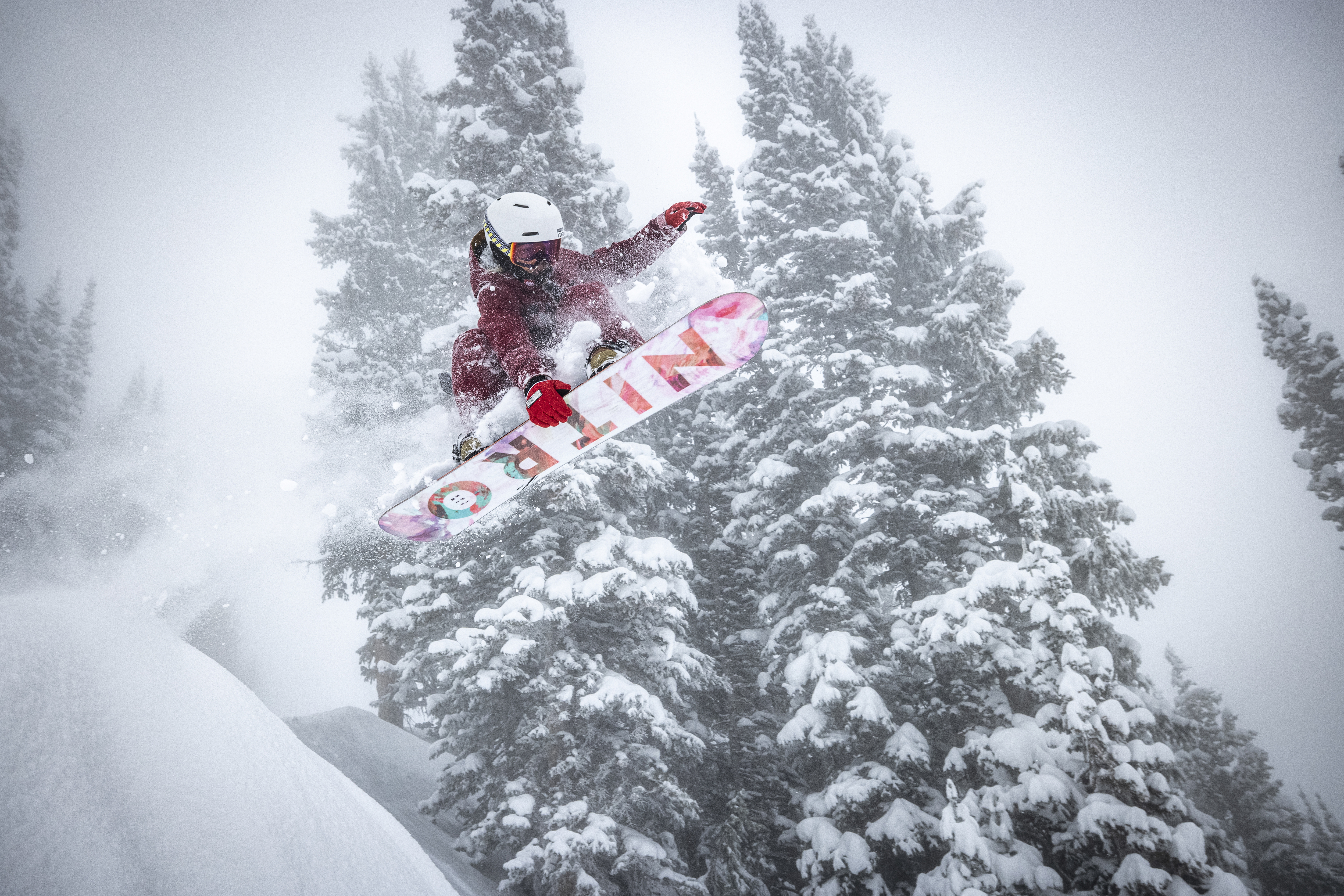 Female jumping off a snowy cliff at Snowbird on a snowy day