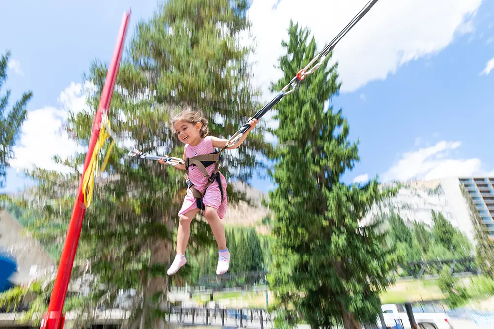 Kid jumping on the bungee trampoline - a summer activity at Snowbird
