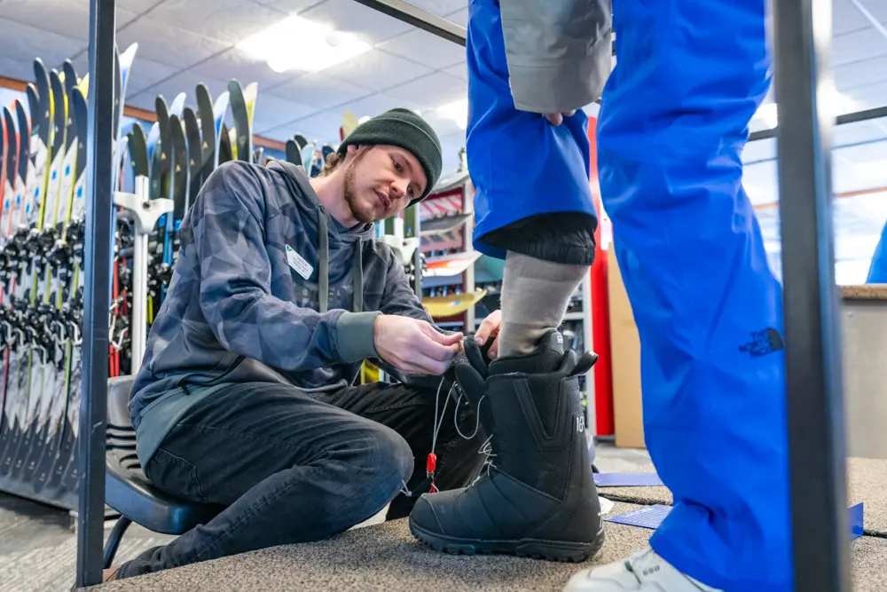 Rental technician helping fit a Snowboard Boot at Snowbird Sports