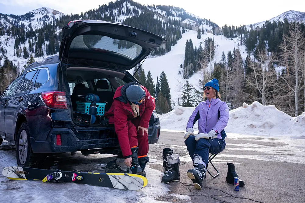 Couple putting on ski boots in the back of a Subaru