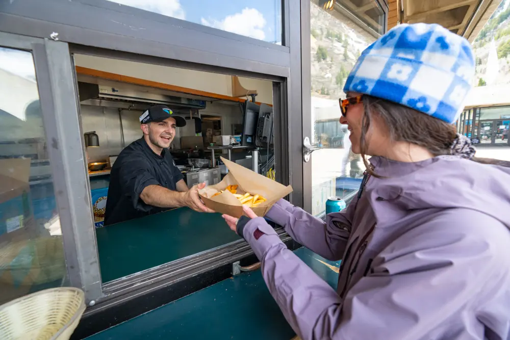 skier receiving fries from The Birdfeeder restaurant at Snowbird