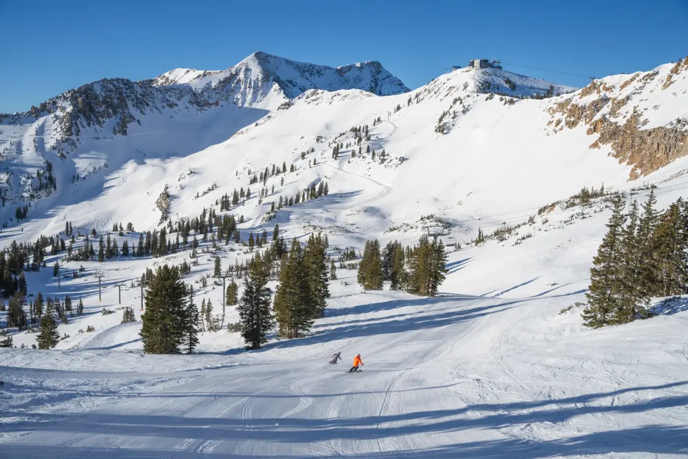 2 people skiing a groomer in Mineral basin surrounded by mountain views