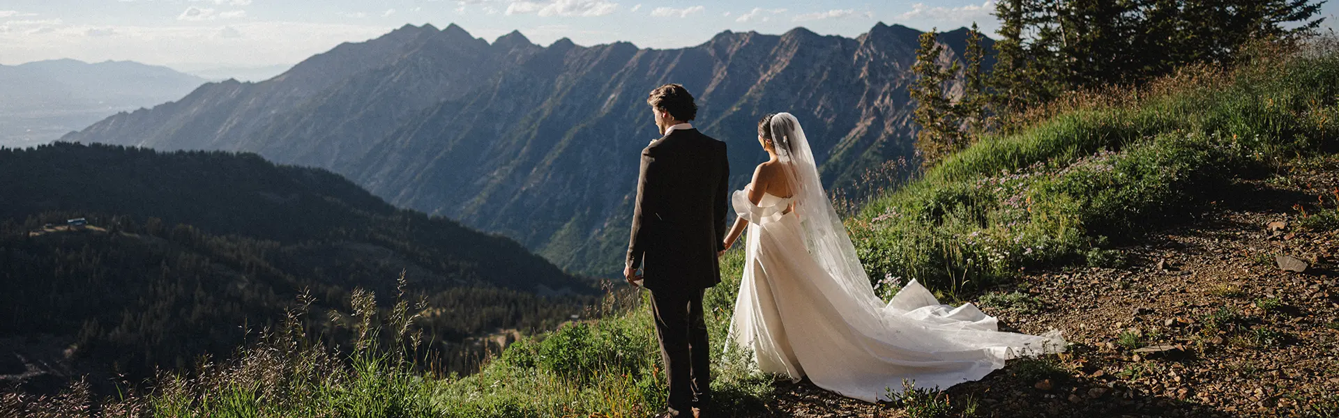 Wedding couple gazes out over mountain view from Snowbird's Summit, one of Snowbird's mountain wedding venues