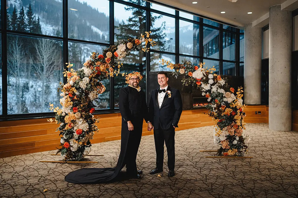Grooms pose in front of floral arch at Snowbird's Golden Cliff wedding venue