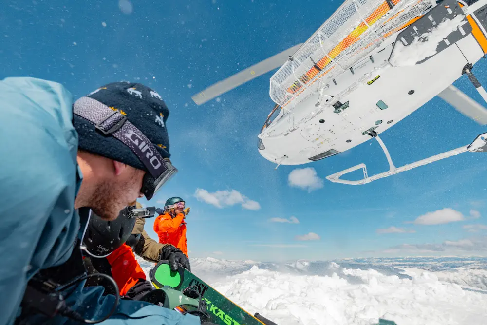 Group ducks down below helicopter while heli skiing at Snowbird with a Mountain Collective Pass