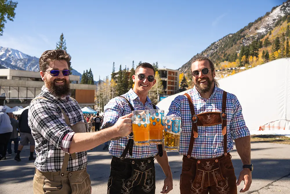 Guys in lederhosen cheersing beers at Snowbird's Oktoberfest