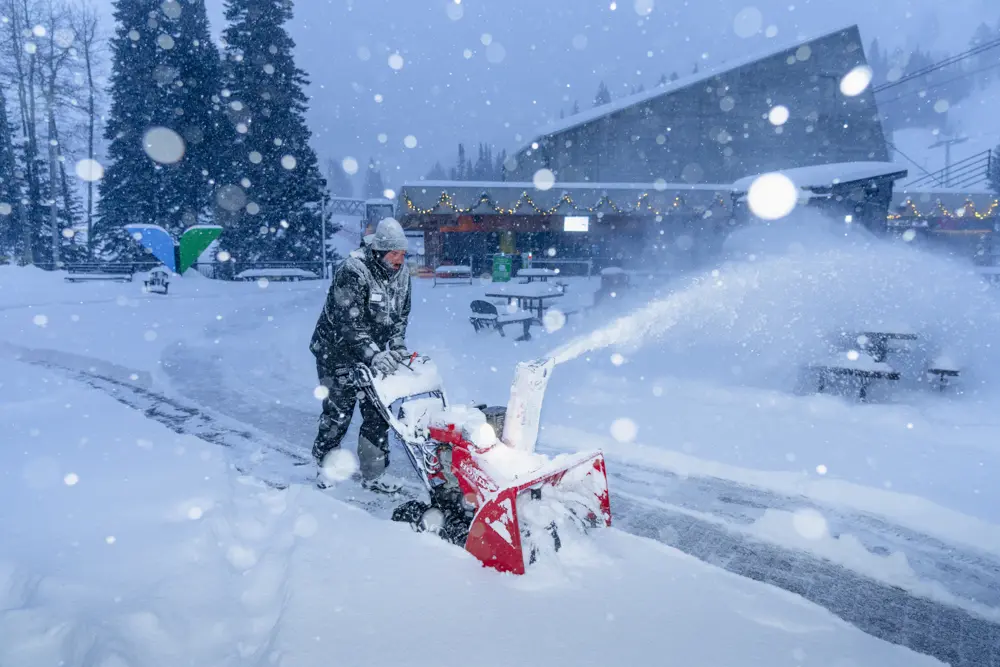 Ski resort employee uses snowblower on the Snowbird Plaza deck in the dark