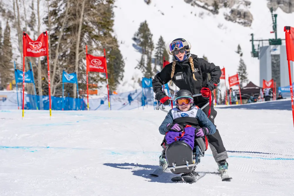 Volunteer works with sit skier at Wasatch Adaptive Sports event