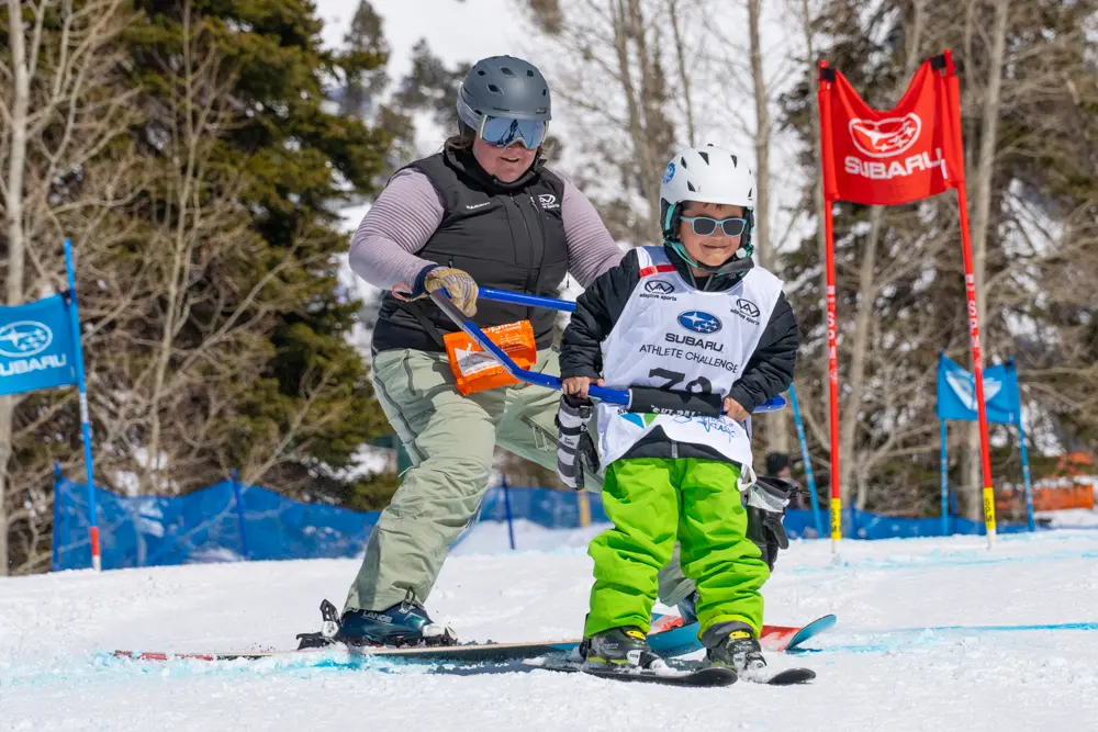 Kid and Wasatch Adaptive Sports instructor ski with adaptive equipment at Snowbird