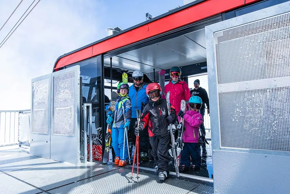 Family getting off The Tram with skis and snowboards