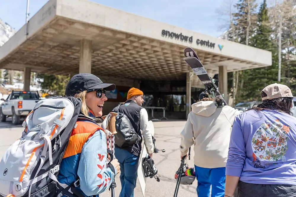 Group of friends walks towards the Snowbird Center with ski gear