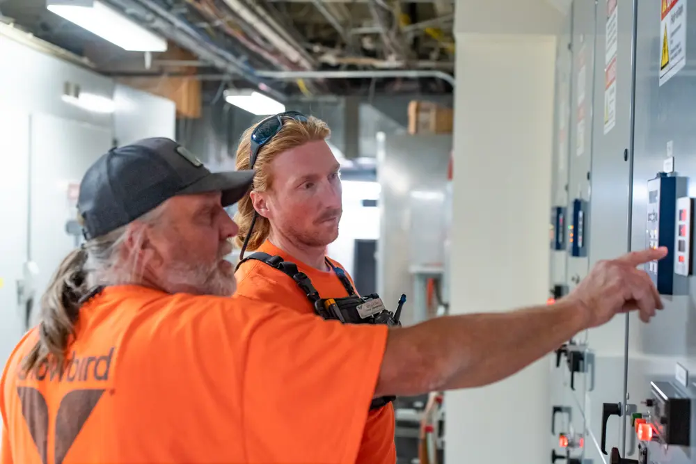 2 maintenance workers at Snowbird ski resort point to an electric panel