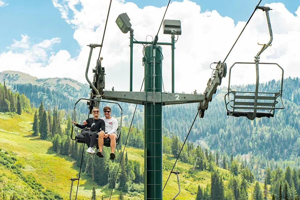 Couple rides the lift together at Snowbird during the summer, one of the amenities of a wedding at Snowbird