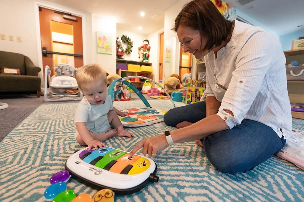 Superior Childcare staff plays a toy piano with a childcare goer