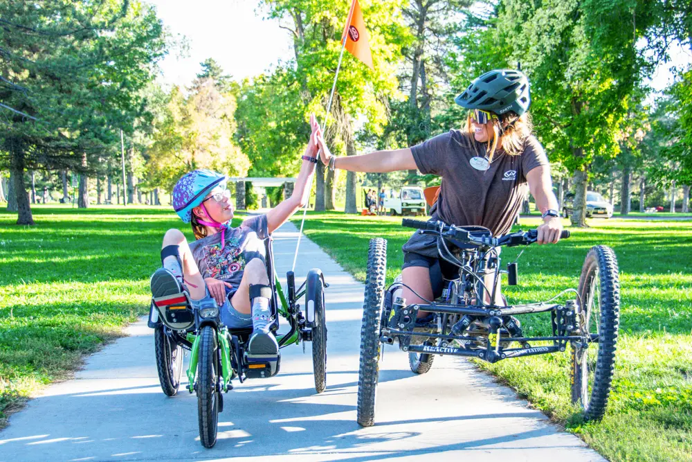 Biker and instructor high-five during a Wasatch Adaptive Sports lesson
