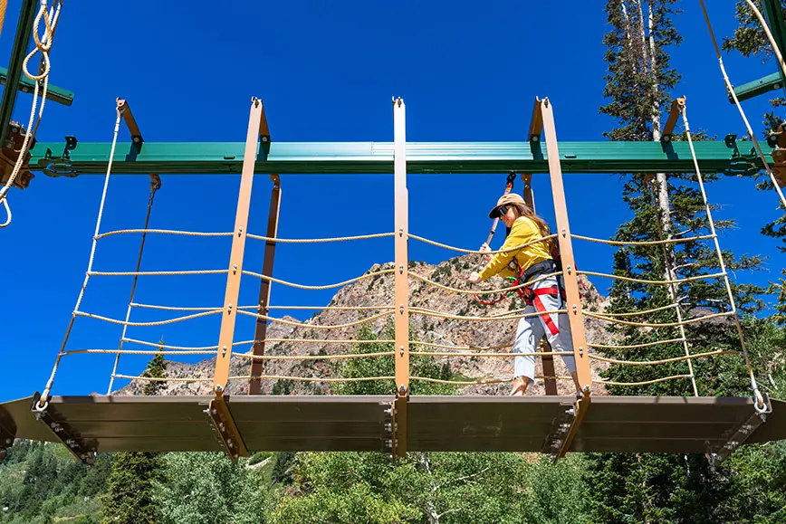 Woman walks across a bridge on Snowbird's new ropes course