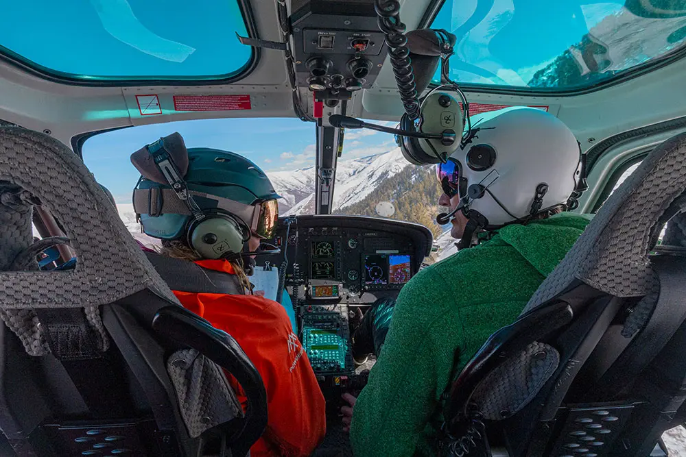 2 people in a helicopter with headsets on during a day of heli skiing