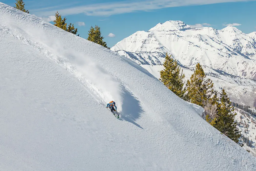 Skier in powder with Timp behind during a day with Powderbird