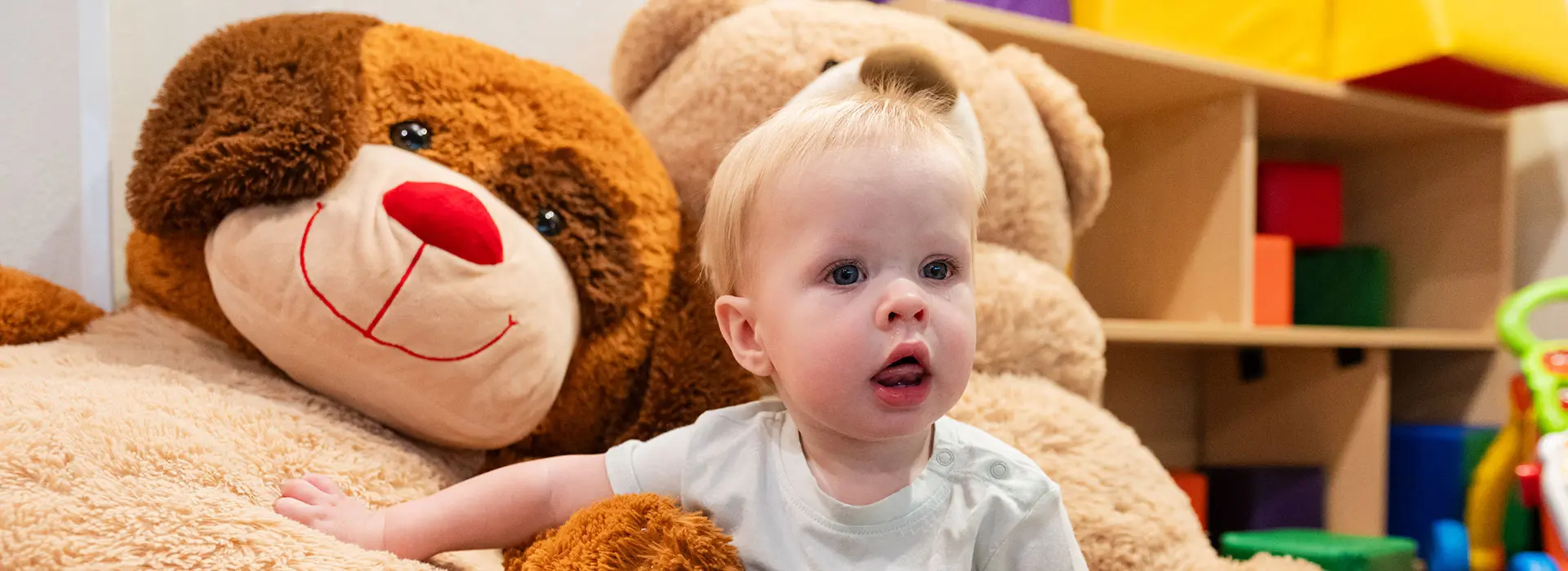 Kid at Superior Childcare with big stuffed animals