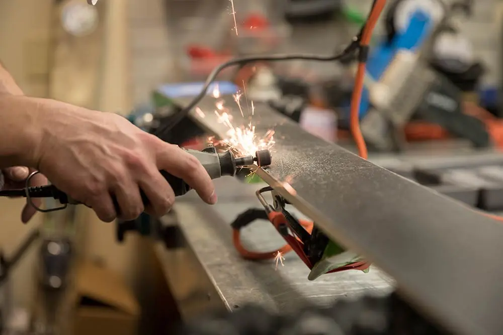 Ski repair at Cliff Sports at Snowbird, technician using a grinder