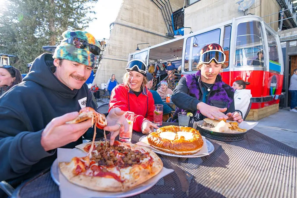 Group eats pizza at the Tram Bar on the patio in the sun at Snowbird