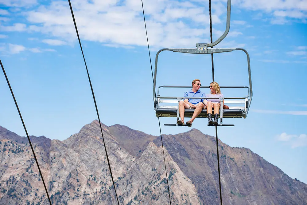 Couple rides the Peruvian Chairlift, with the mountains in the background
