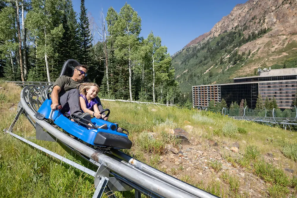 Dad and daughter riding the mountain coaster together at Snowbird with an All-Day Activity Pass