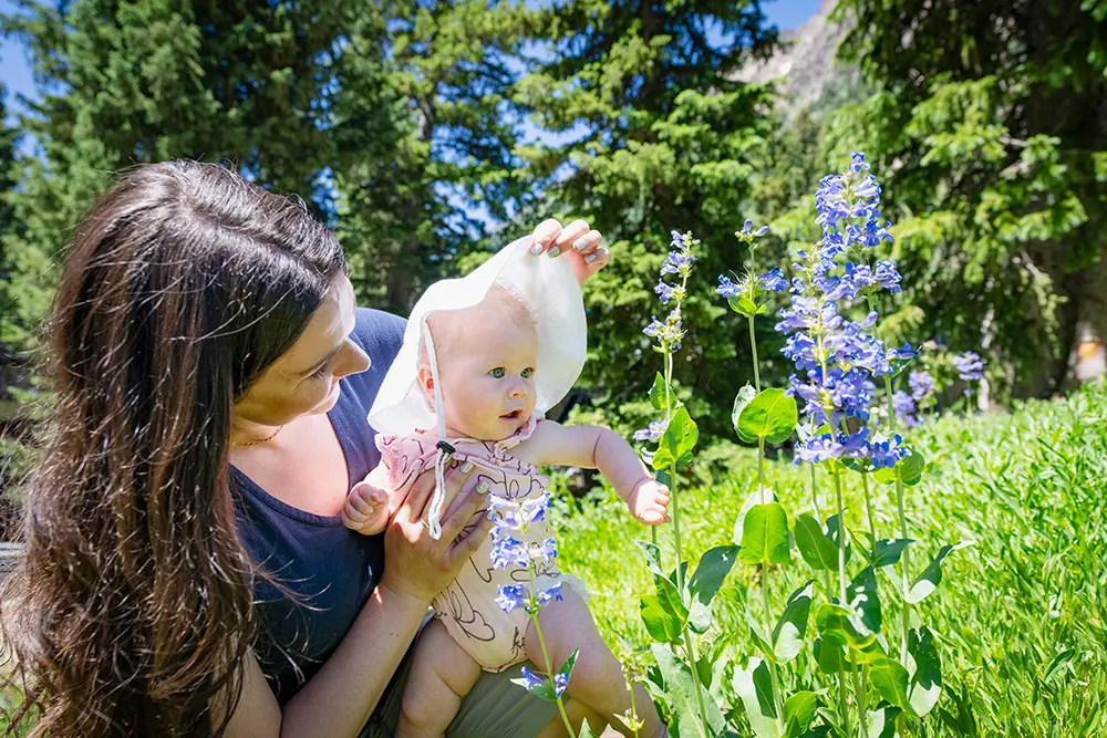 Child in Superior Childcare looking at flowers in a sun hat, being held by an instructor