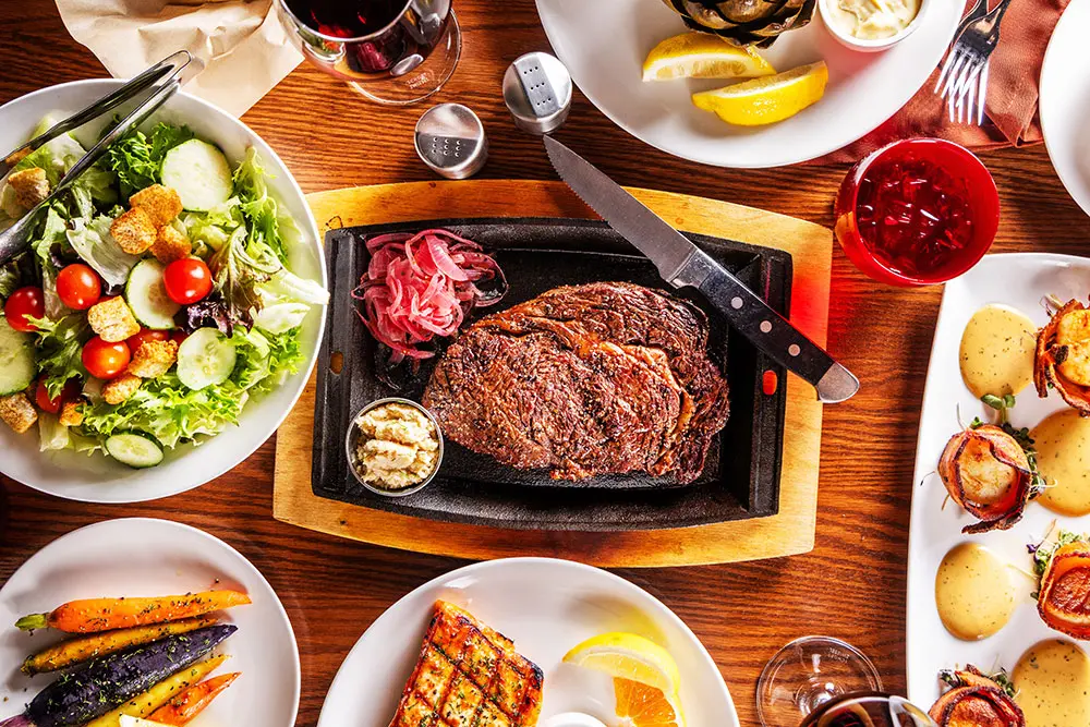 Steak at the Steak Pit surrounded by sides and appetizers.
