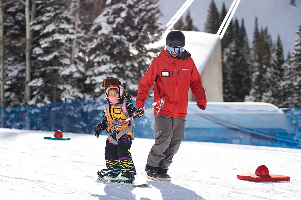Snowboarder in a youth lesson at snowbird skis down chickadee with a Mountain School Instructor