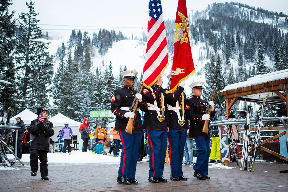 Military member march with flags at Snowbird's Highly Decorated event
