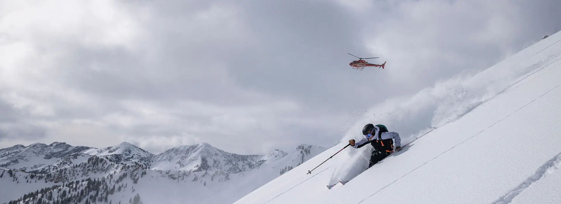 Skier in powder under a helicopter with Powderbird helicopter skiing in Utah, near Snowbird