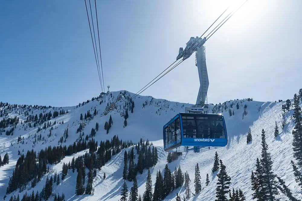 Blue tram with the Snowbird Cirque in the background during the summer