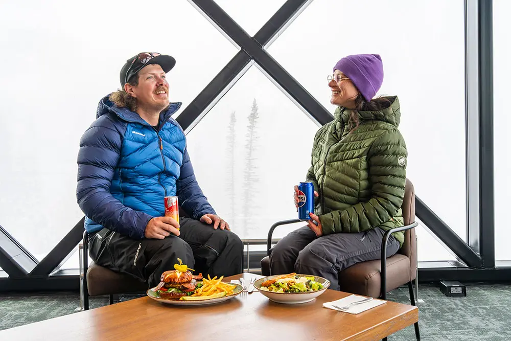 A couple enjoys lunch at the nest next to floor-to-ceiling windows