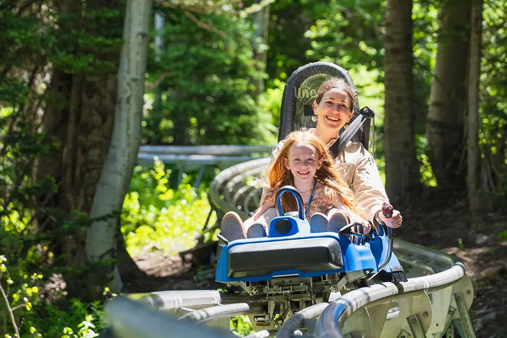 Family rides the Mountain Coaster at Snowbird through the trees