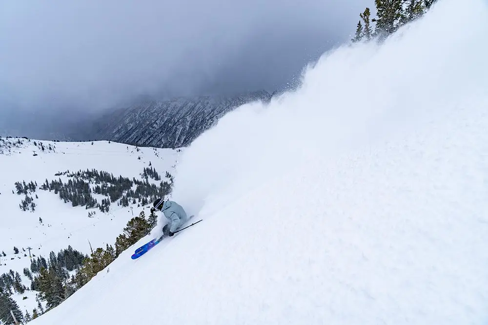 Skier makes a deep turn with a dark background during a February storm at Snowbird