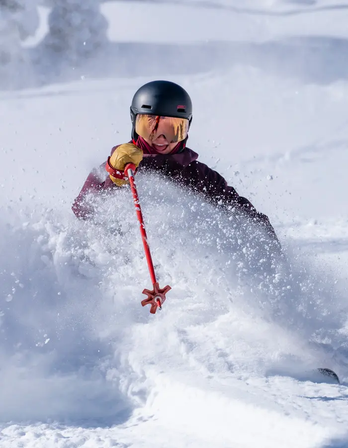 Mobile hero for season passes of a skier in deep powder smiling