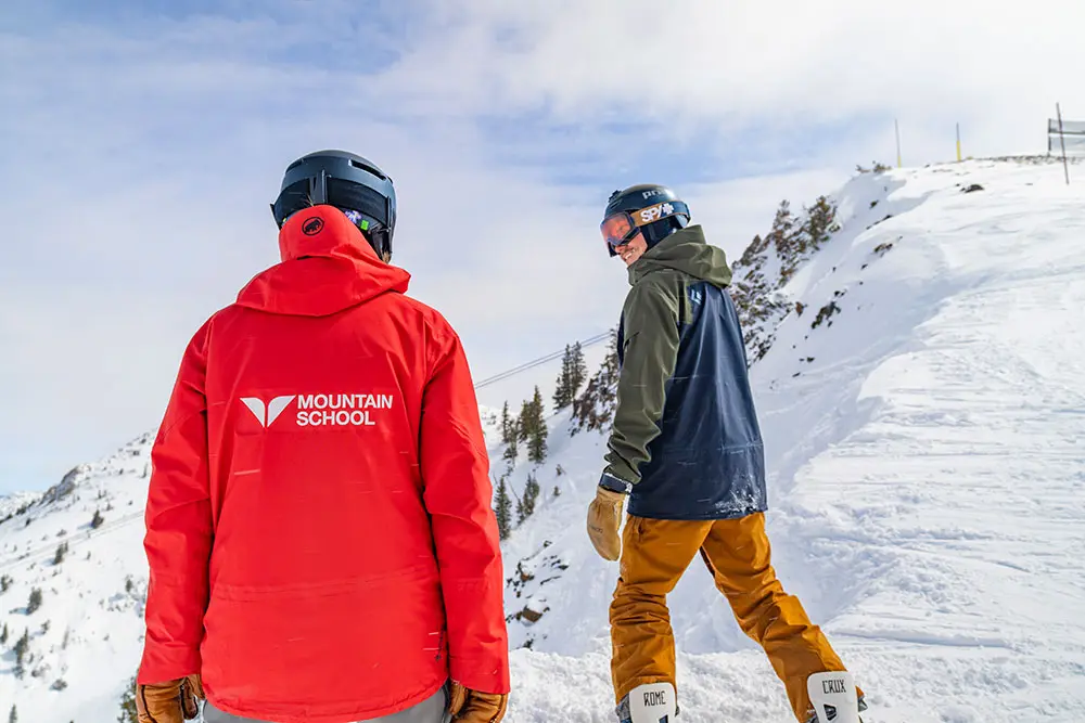 Mountain School employee talks to a Snowboarder on the Cirque during an Adult Mountain Experience lesson