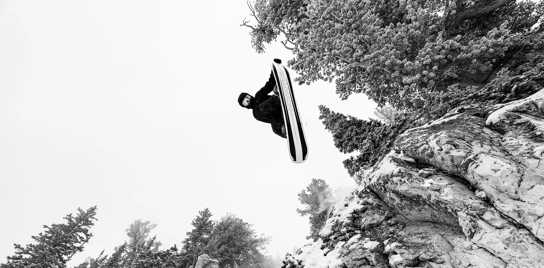 Snowboarder hits a cliff in black and white