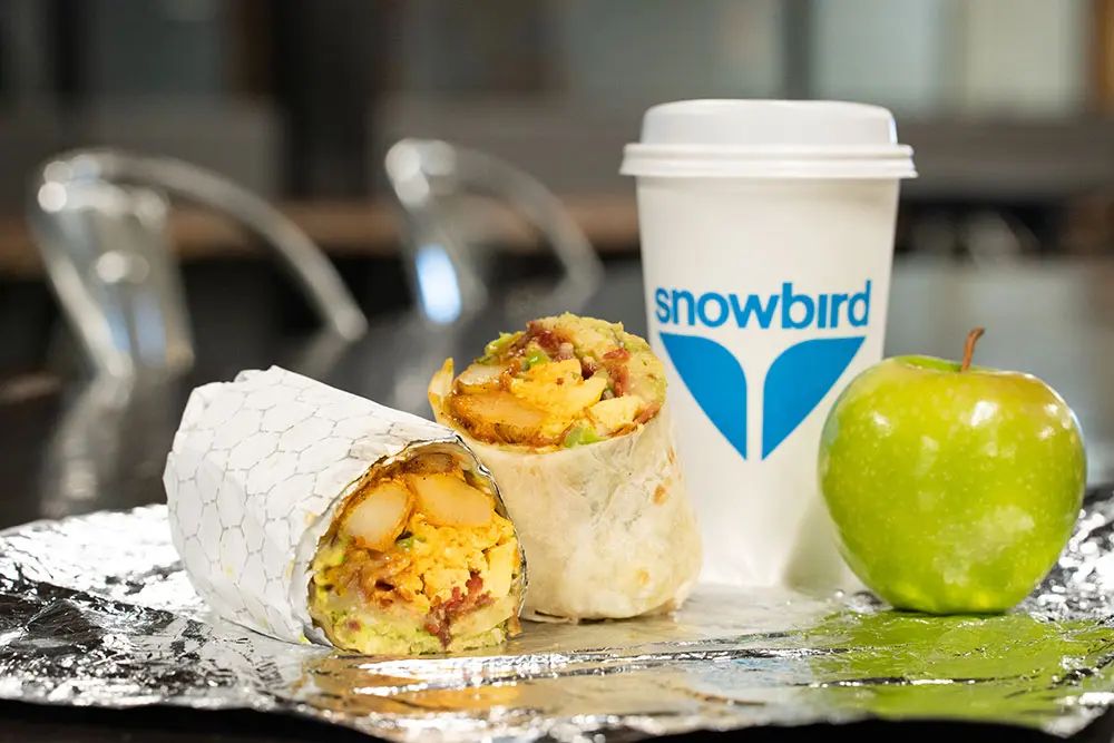 Breakfast burrito from General Gritts next to coffee and an apple