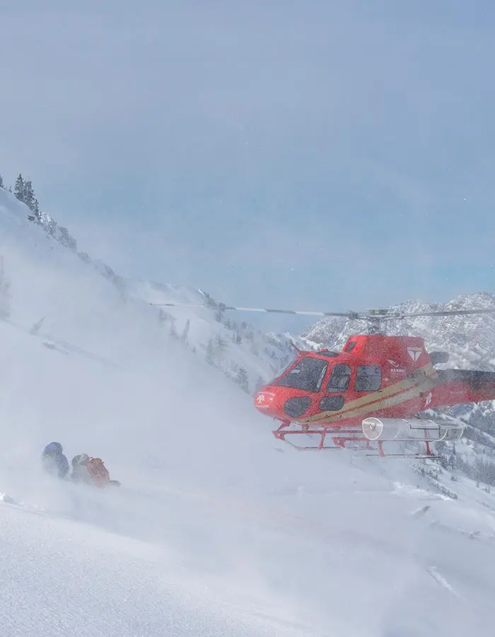 Mobile image of helicopter landing next to skiers
