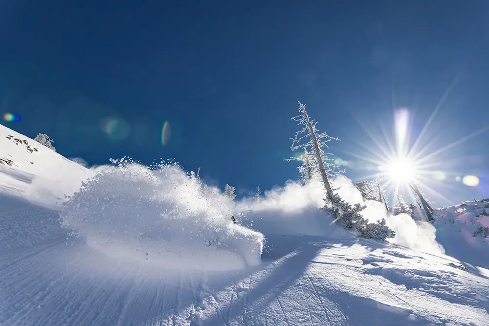 A skier in a deep powder turn on a bluebird day at Snowbird in March