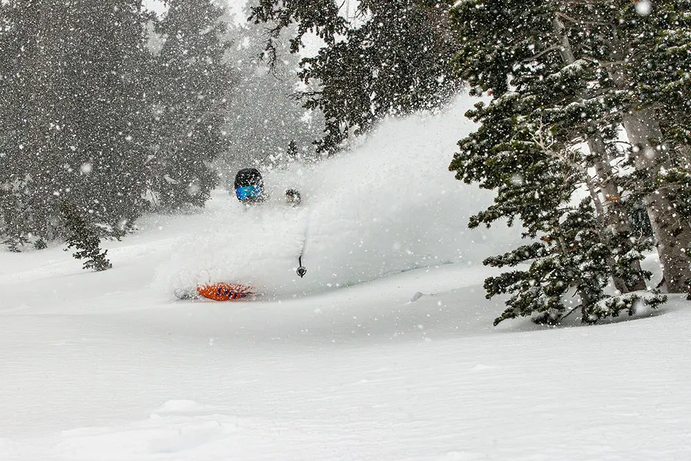Skier with snow falling and a powder cloud trailing them