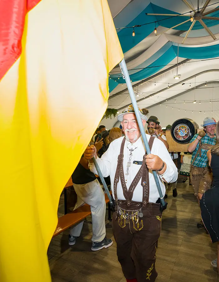 Mobile hero of an oktoberfest flag bearer walking in followed by the official keg