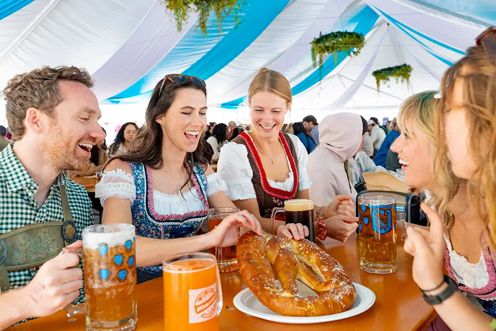Oktoberfest Halle tent at Snowbird-group eating a giant pretzels, holding giant beers