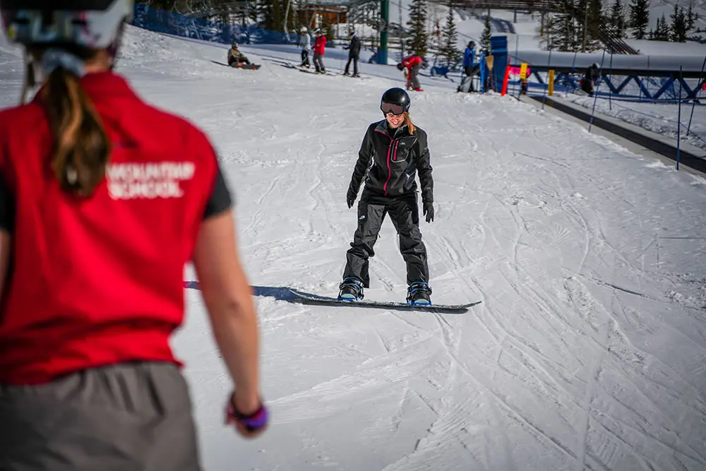 Mountain School instructor works with an adult snowboarder during an Adult Beginner Lesson