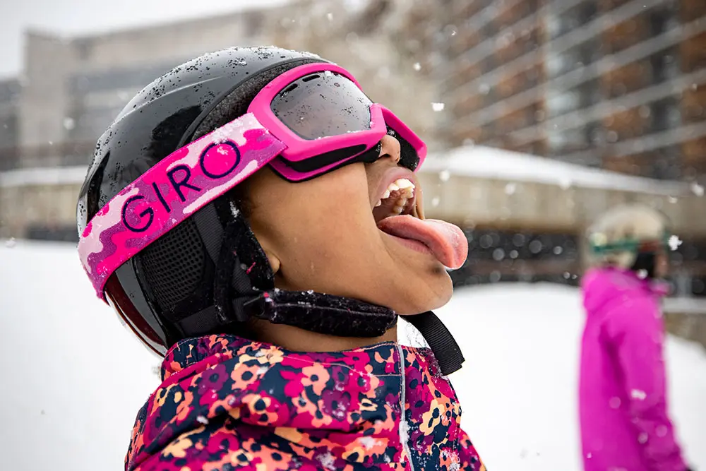Kid with youth lift ticket eating snow as it falls at Snowbird