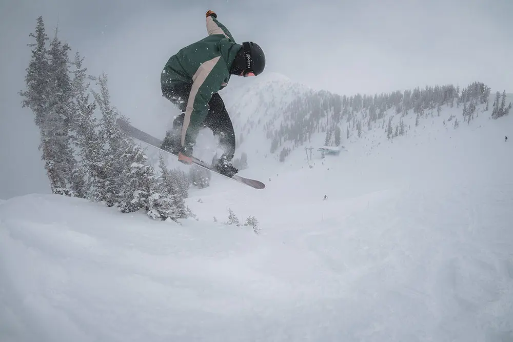 Snowboarder jumps off a bump at Snowbird above Peruvian lift during the Adult Snowboard Camp with the Adult Snowboard Camp Lodging Special.