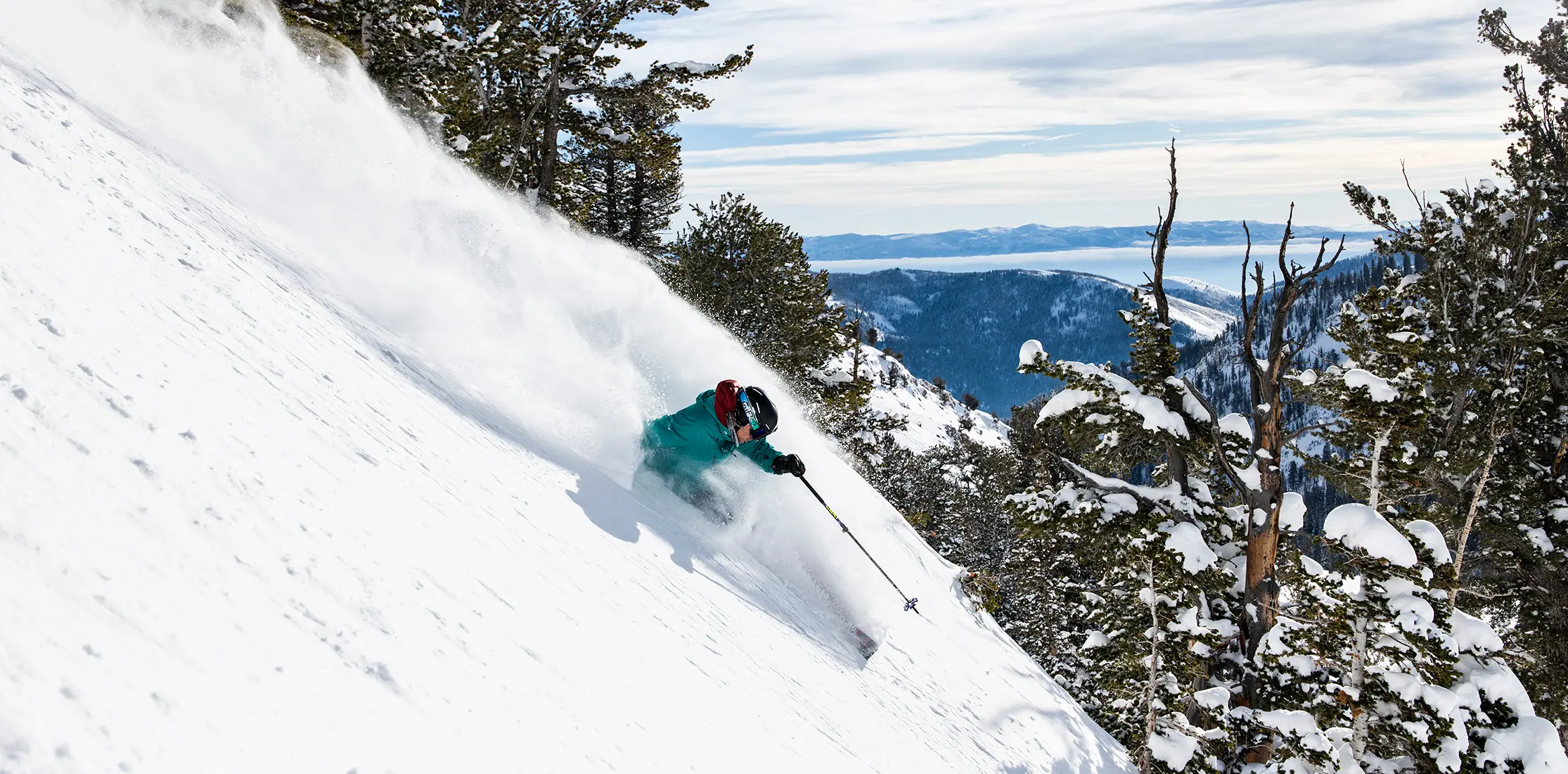 Skier in powder with the salt lake valley in the background at Snowbird with a Season Pass